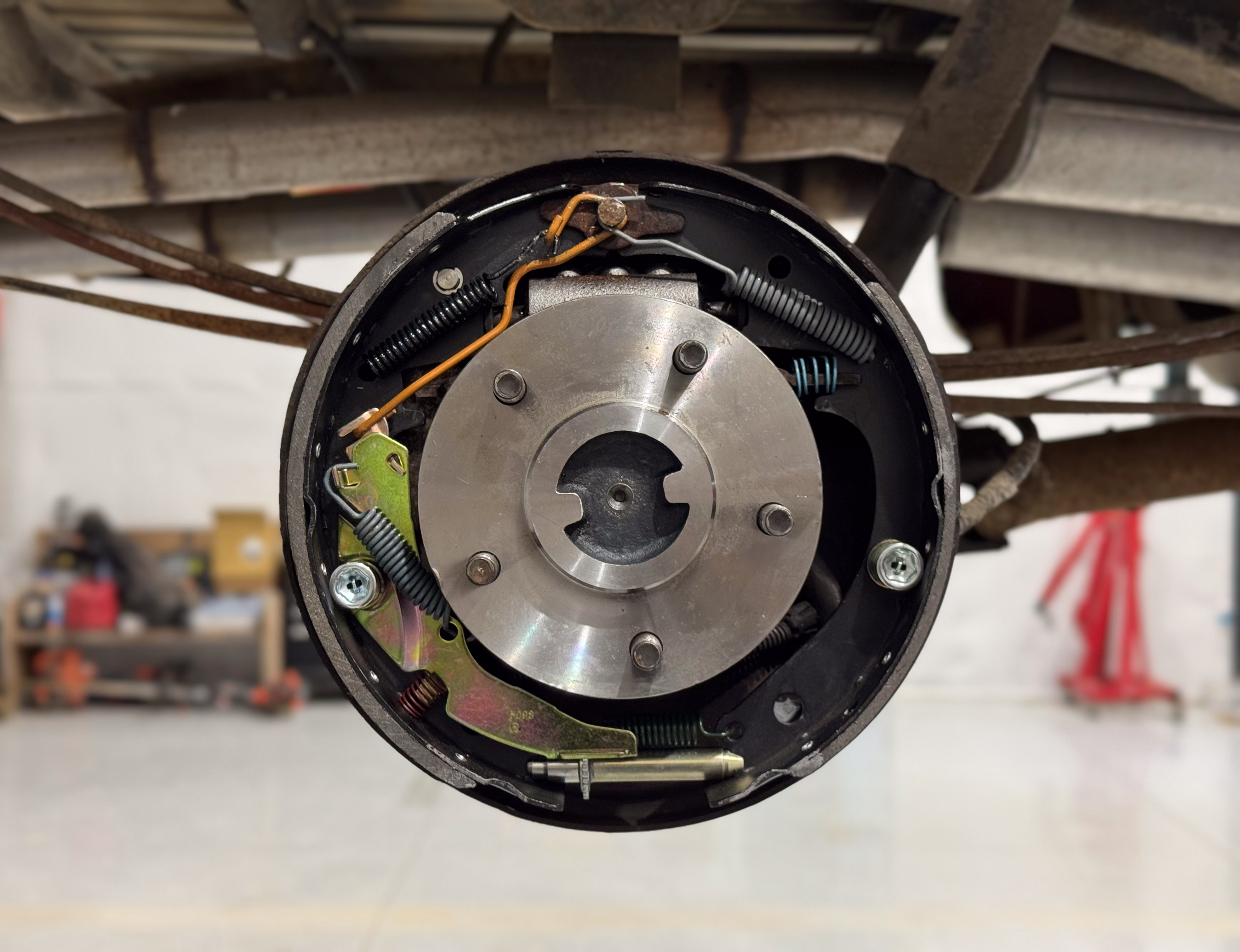 A photo showing a shiny new axle and new brake shoes installed on a vehicle