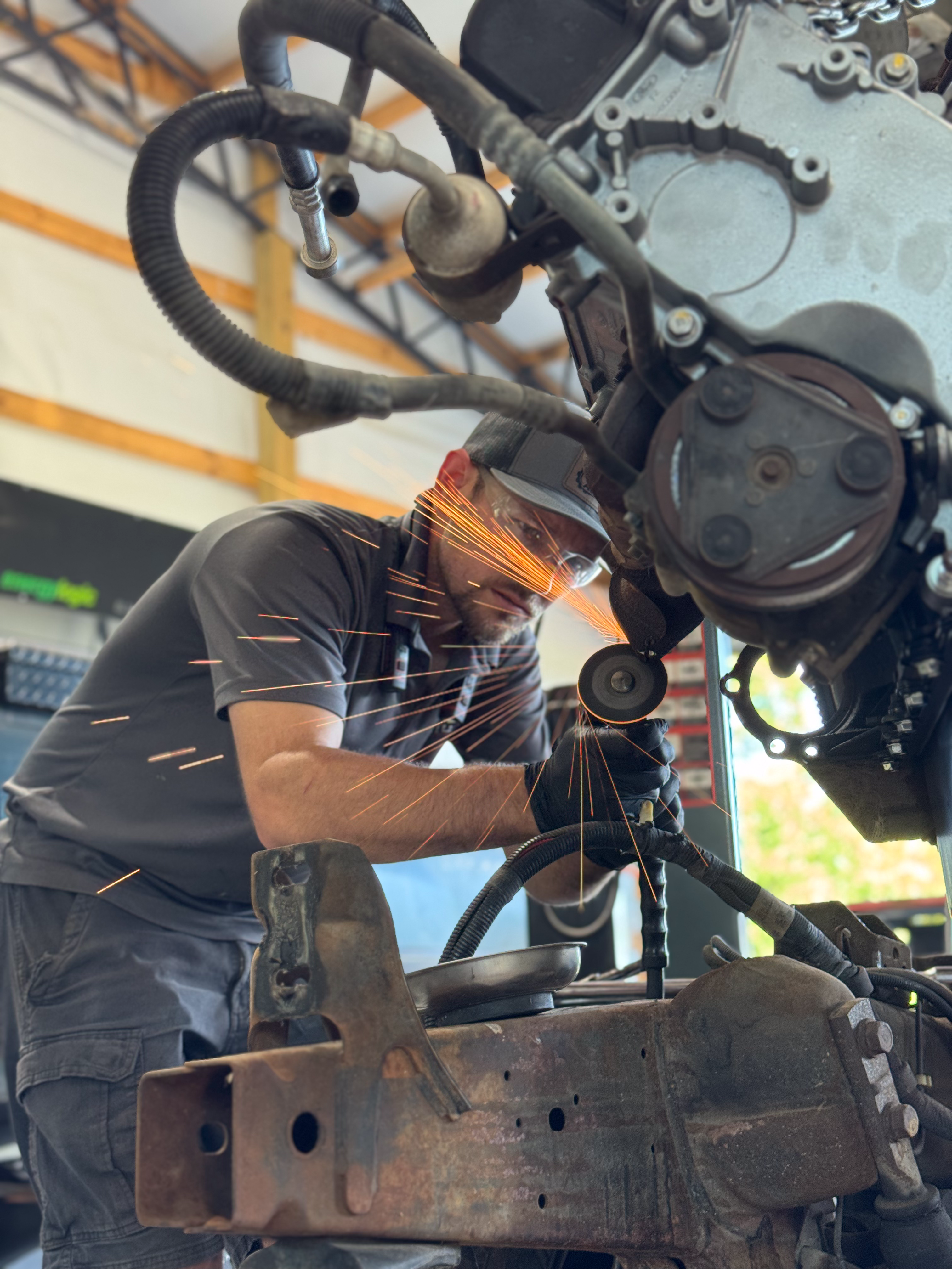 An image showing a man using a cut-off wheel to cut a broken stud on an engine with sparks flying.