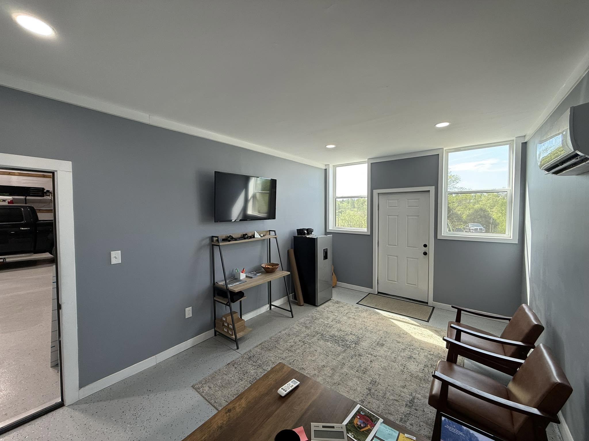 An image of the waiting room which incluse two chairs a TV and windows